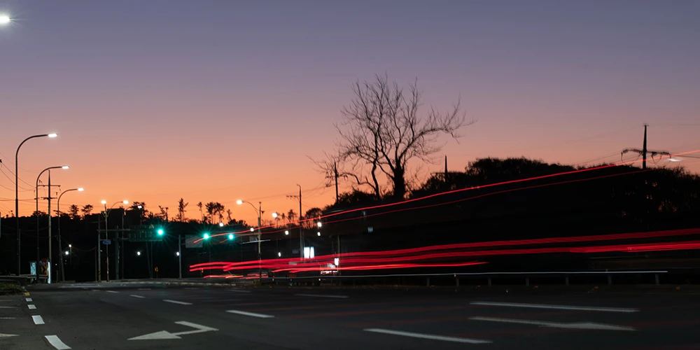 street lights illuminate the road during sunset