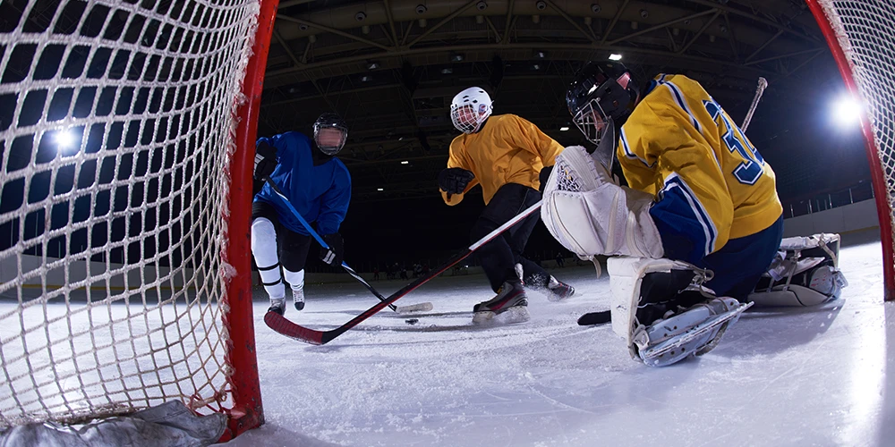 three mens playing ice hockey in indoor hockey rink